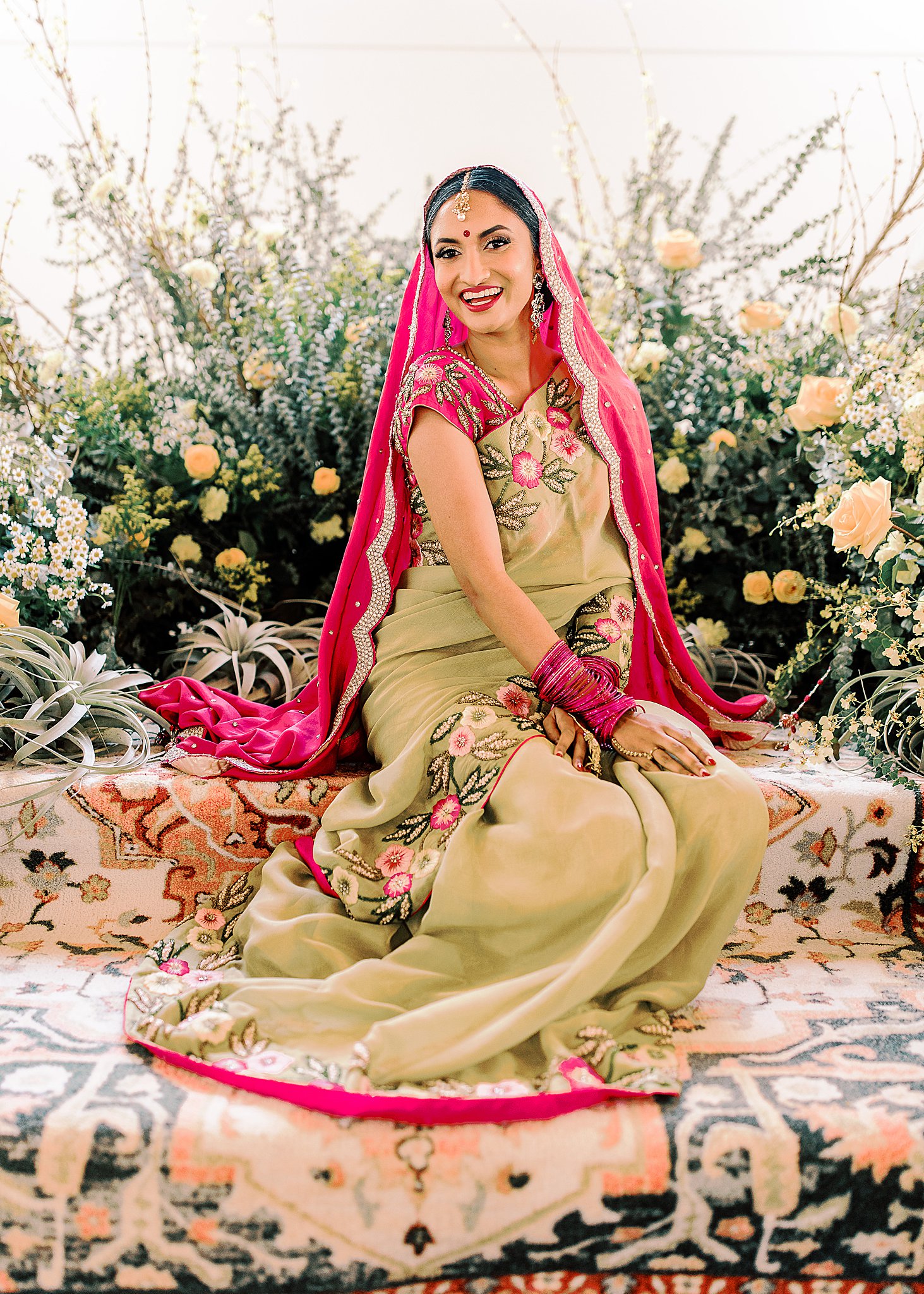 Gorgeous Indian bride in pink and gold lehenga surrounded by yellow roses