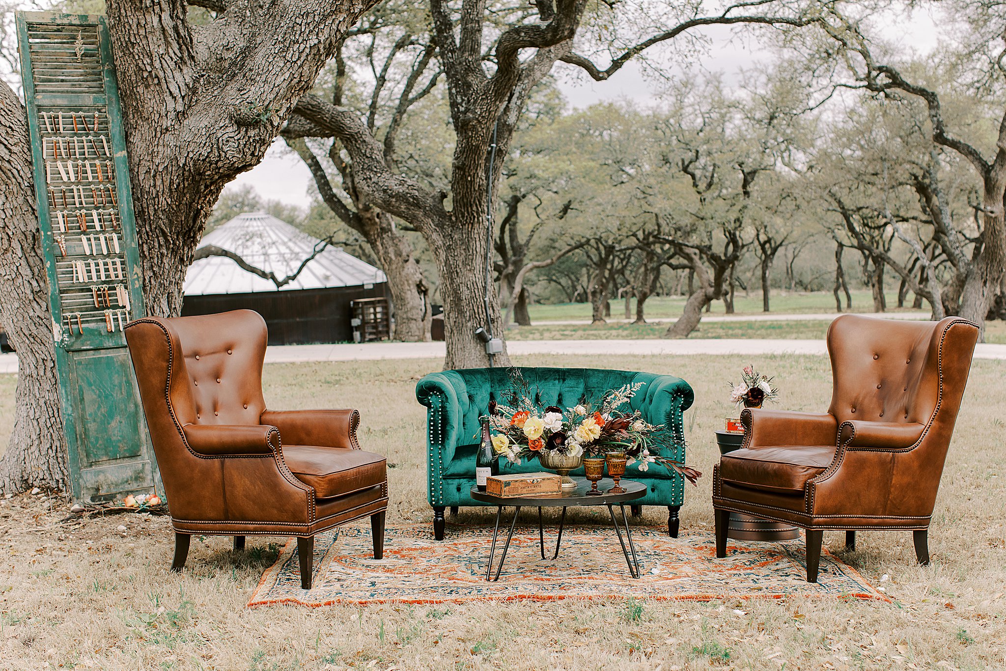 Fall rustic outdoor wedding with green velvet chair, leather chairs